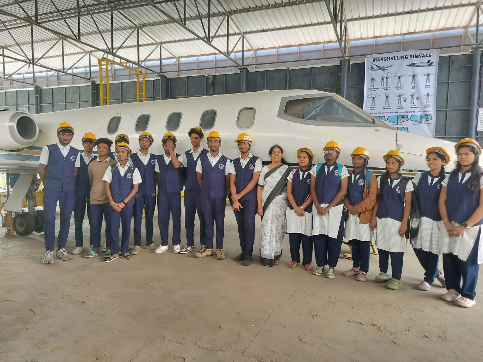 Students in safety helmets beside an aircraft on the aeronautical trip